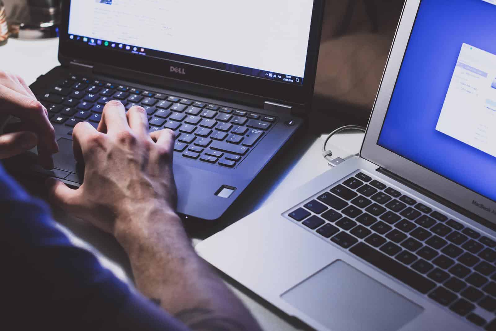 Man working with two laptops