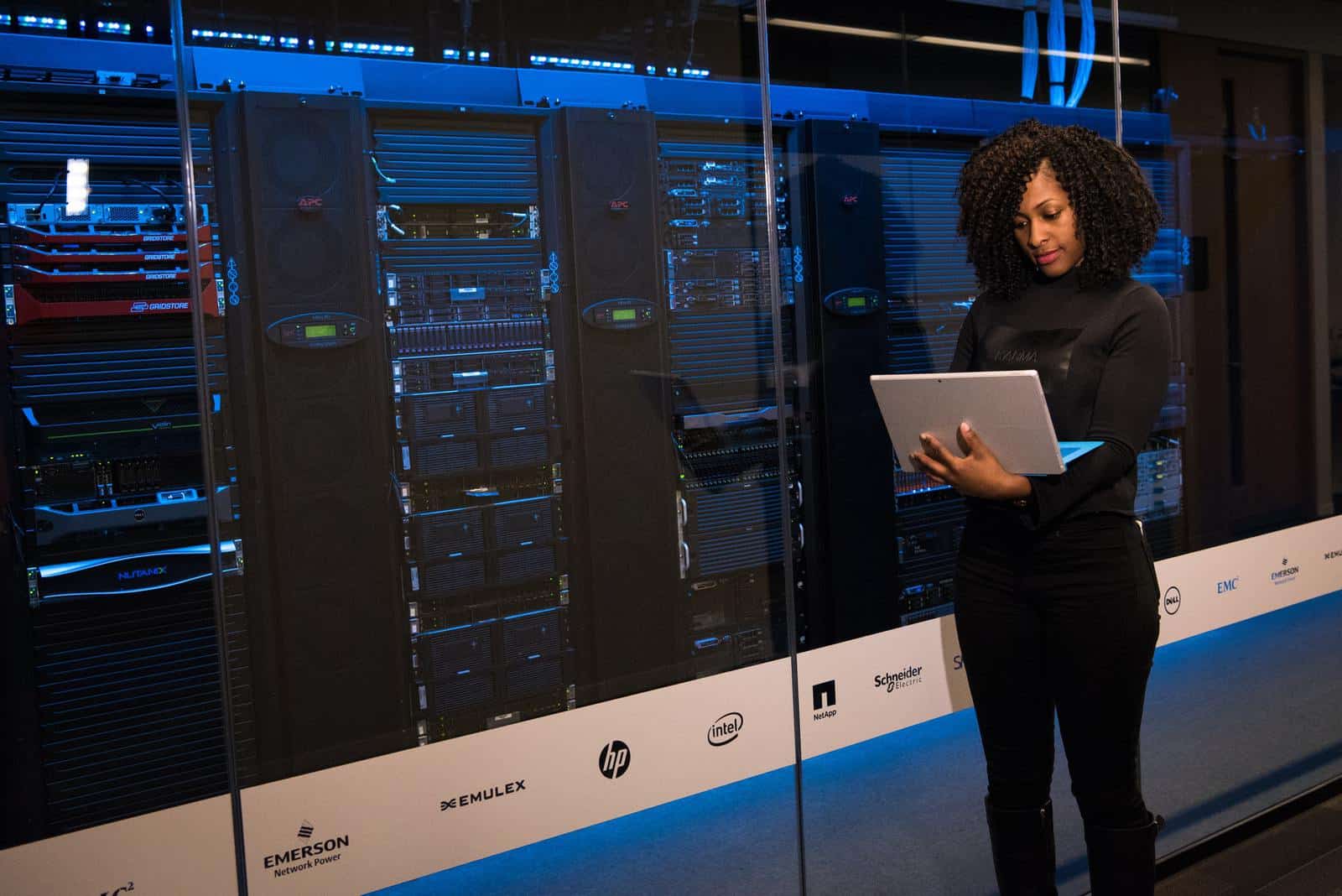 Woman using laptop next to server