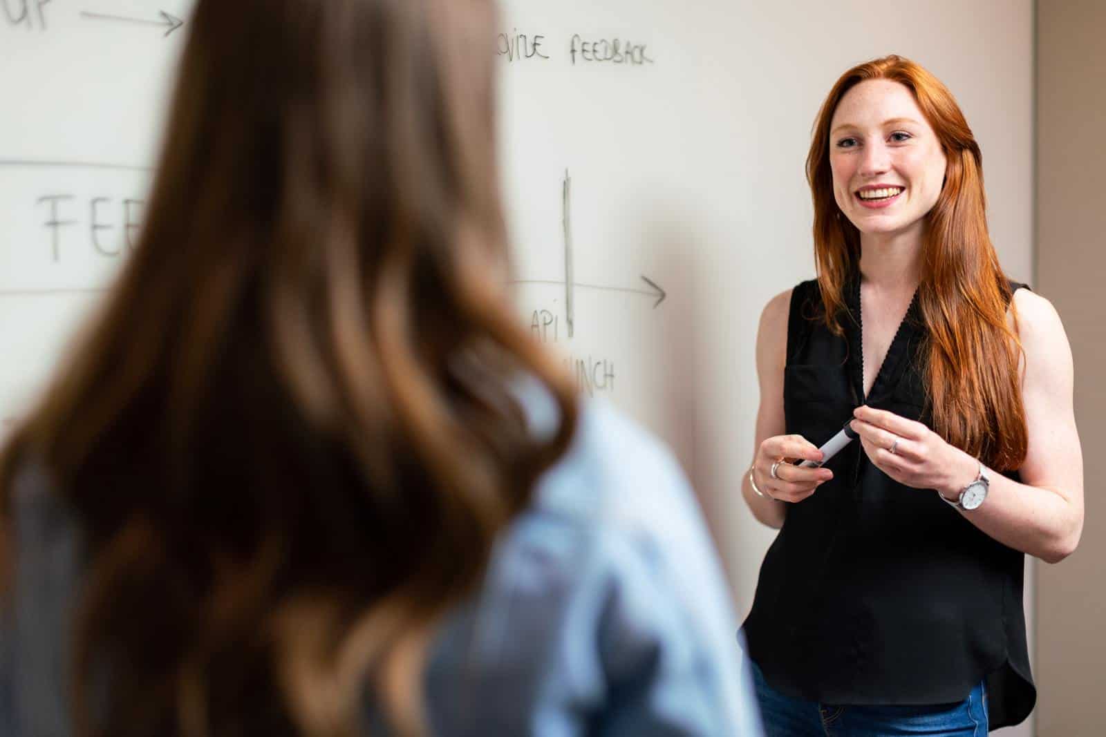 Two women standing in front of whiteboard