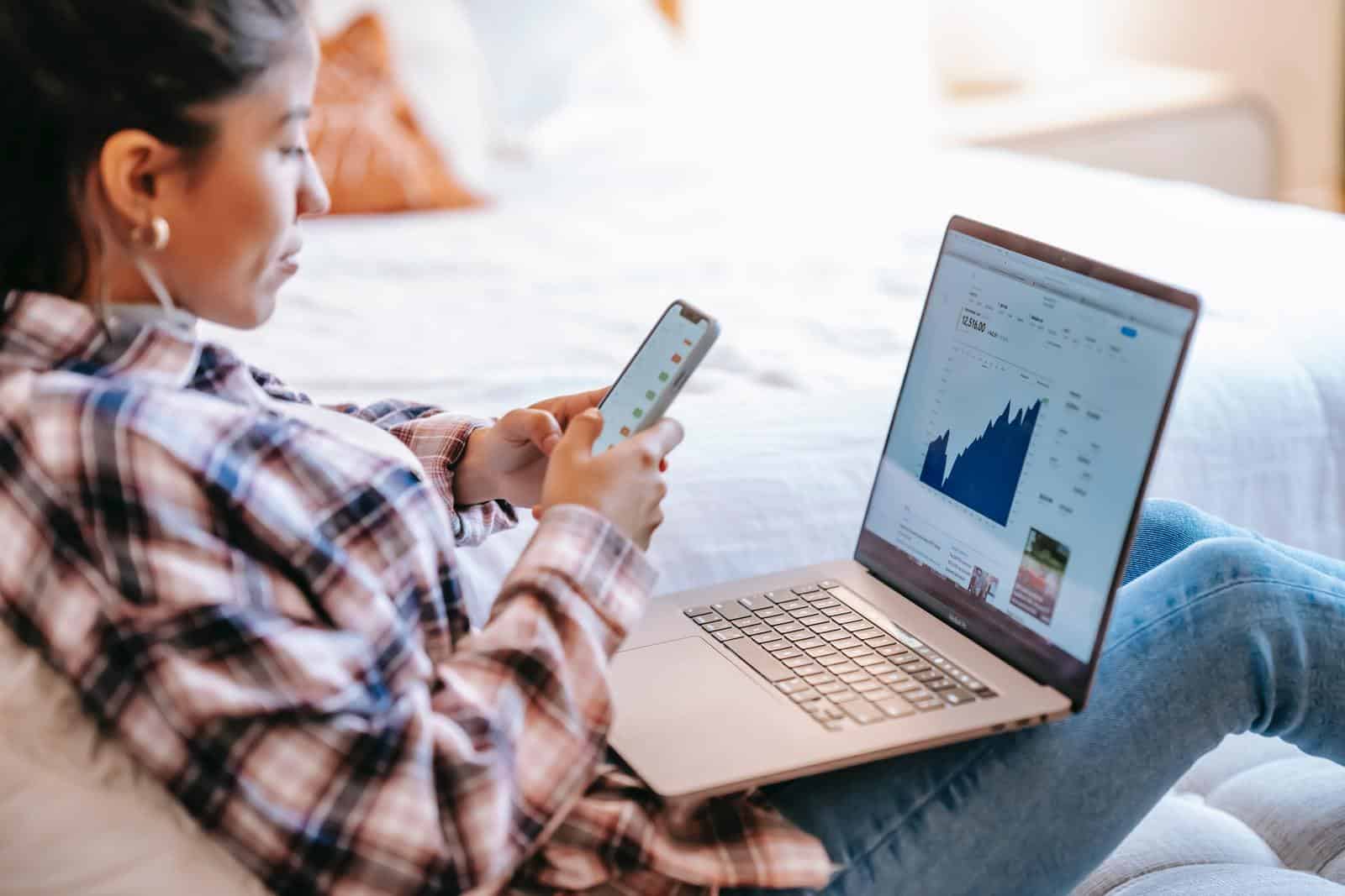 Woman holding phone and laptop