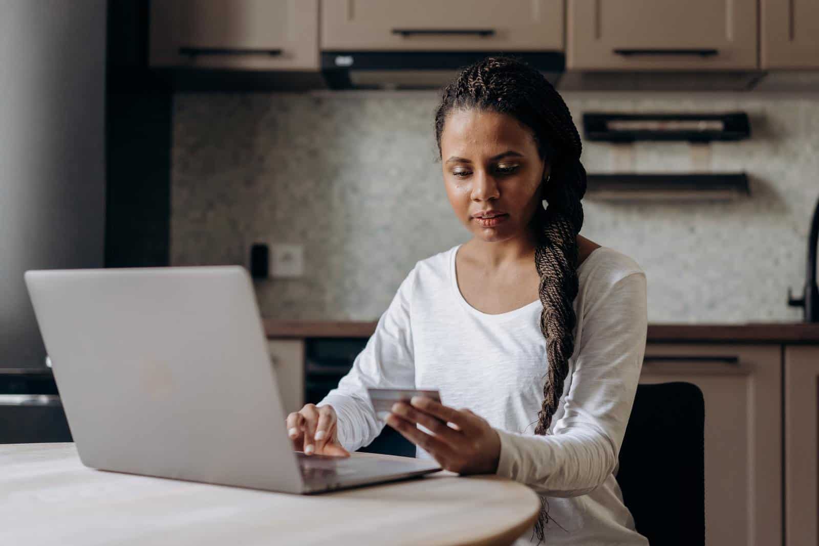 Person using laptop and holding credit card 