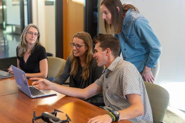 group of young people using macbook